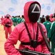 A Squid Game guard standing at the front of a room of contestants